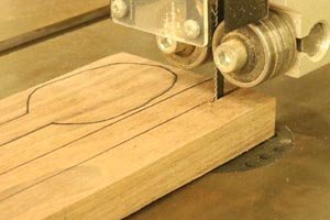 Cut out wooden spoon blanks on band saw.