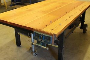 Workbench with wooden top, metal base, wheels, and jack.