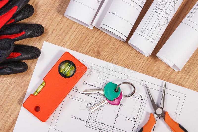 Home keys with electrical drawings, protective gloves and orange work tools, concept of building home. Home keys with blueprints or electrical construction royalty free stock photography