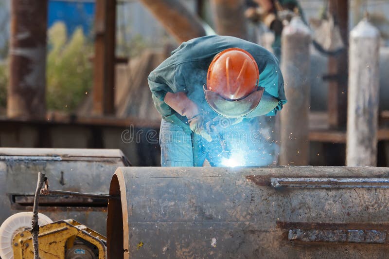 Welding steel and sparks. A worker welding steel on site at a engineering site . The sparks from the arc light the gloves andw elding shield helmet royalty free stock photos