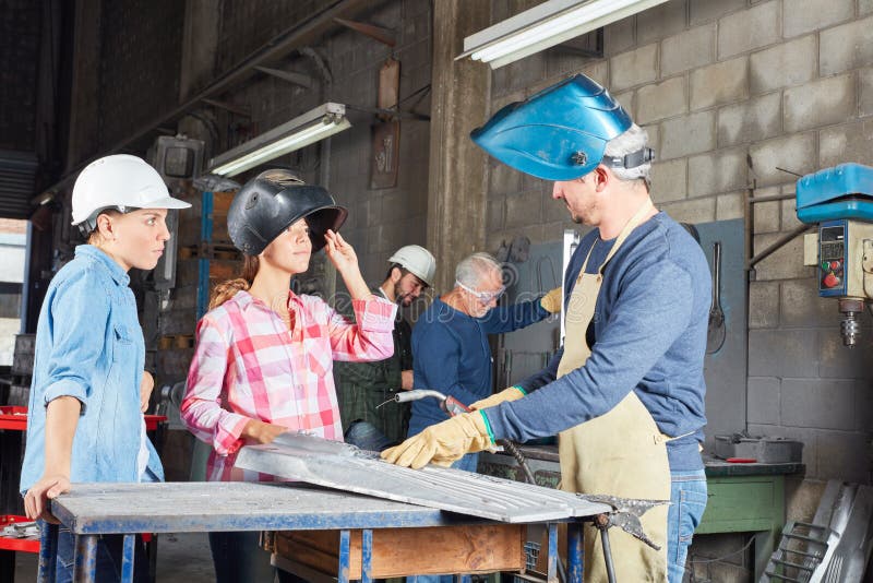 Women in welding apprenticeship lesson. In metallurgy workshop stock photos
